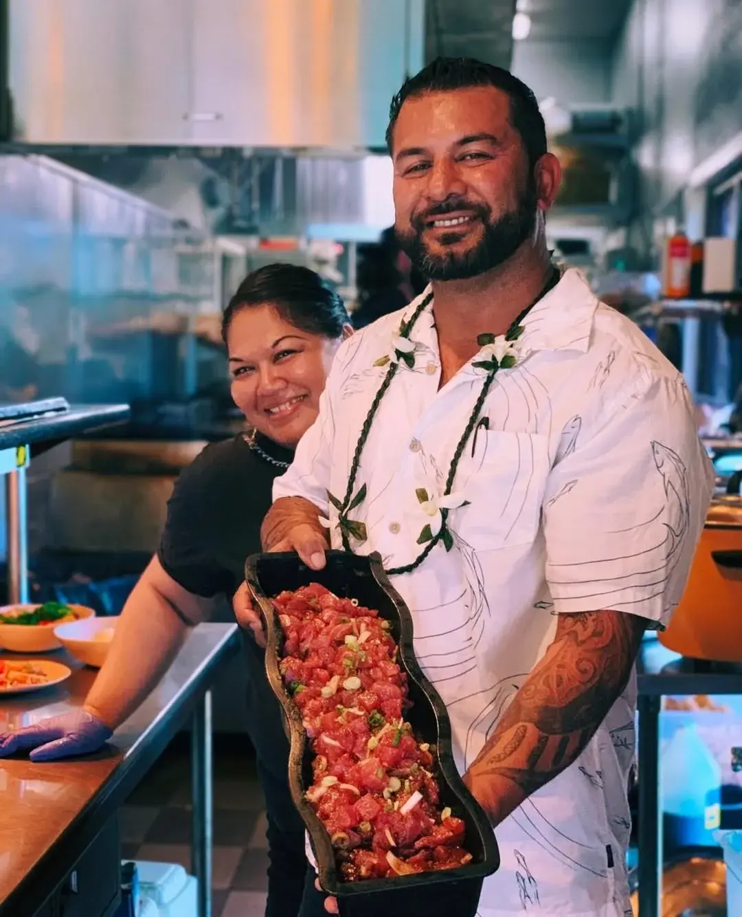 Chef Nakoa Pabre holding a platter of fresh ahi poke in the Umekes kitchen